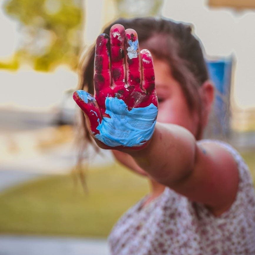 Child's hand covered in red and blue paint