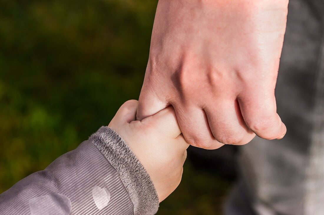 Adult hand holding a child's hand