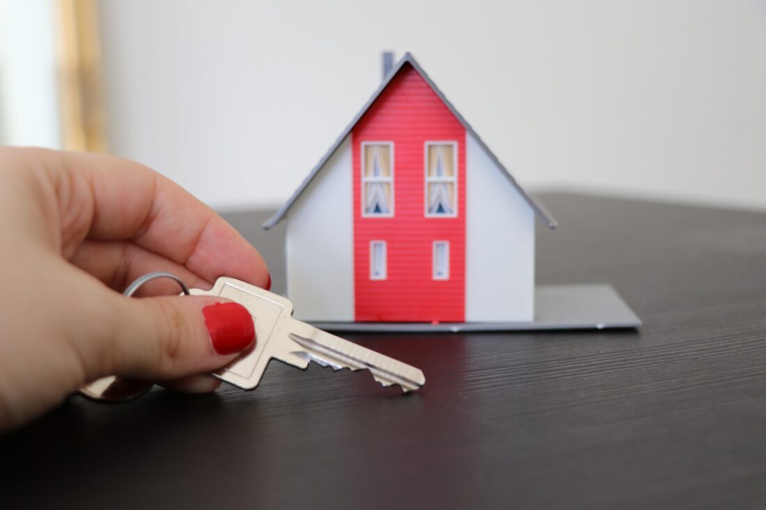 Small model house and hand holding a key