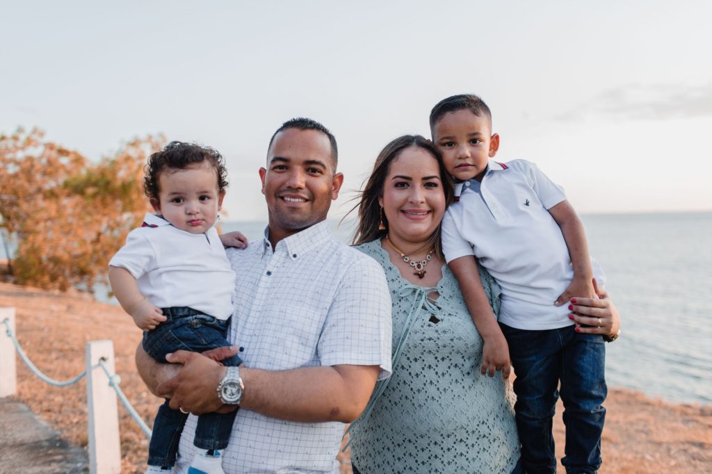 Family smiling outside by the water